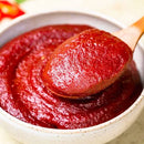 Red chili paste in a bowl with a wooden spoon
