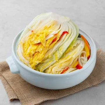 Bowl of pickled cabbage with carrots on a light gray background