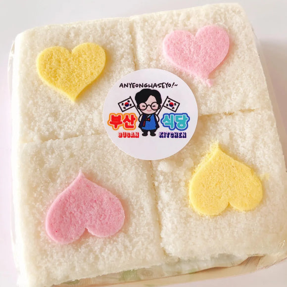 Square piece of rice cake with heart-shaped decorations and a logo in the center.