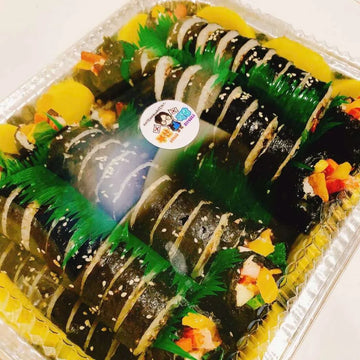 A platter of beef kimbap rolls filled with various ingredients, presented in a disposable aluminum tray.