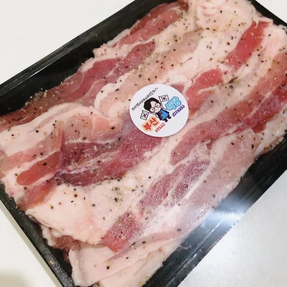 Beef Belly in herbs & salt on a black tray with a brand label.