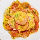 Pan-fried pink sausage slices on a plate, garnished with green herbs.