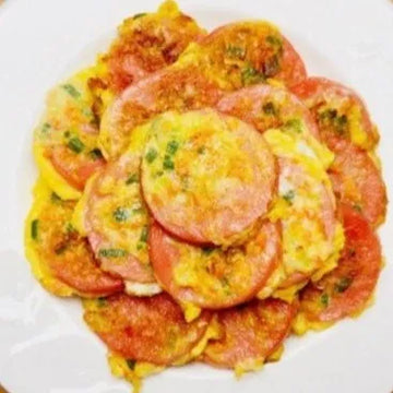 Pan-fried pink sausage slices on a plate, garnished with green herbs.