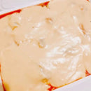 A platter of cheese-topped Korean rice cakes, which appears to be the product described.