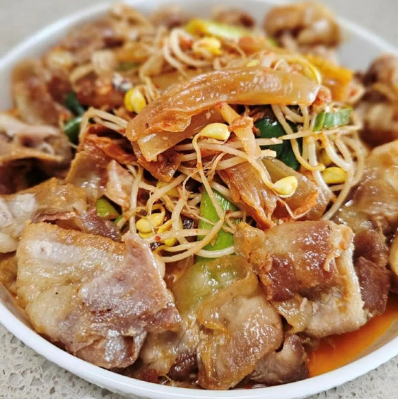 Plated Daepae Samgyup Bokkeum dish with noodles, vegetables, and pieces of meat on a light background