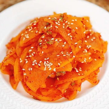 Spicy Seasoned Yellow Pickled Radish with sesame seeds on a white plate