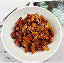 White bowl filled with roasted peanuts and sesame seeds on a light background
