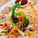 Close-up of a Korean pancake, and a small bowl of dipping sauce.