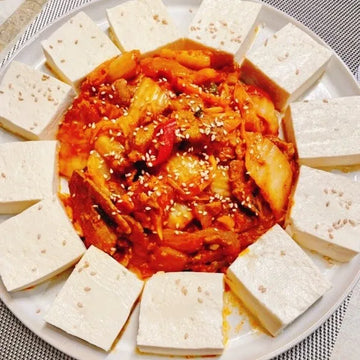 A plate of Dubu Tuna Kimchi, featuring stir-fried kimchi and tuna with sliced tofu arranged around it.