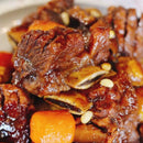Close-up of braised beef with carrots and nuts on a white plate