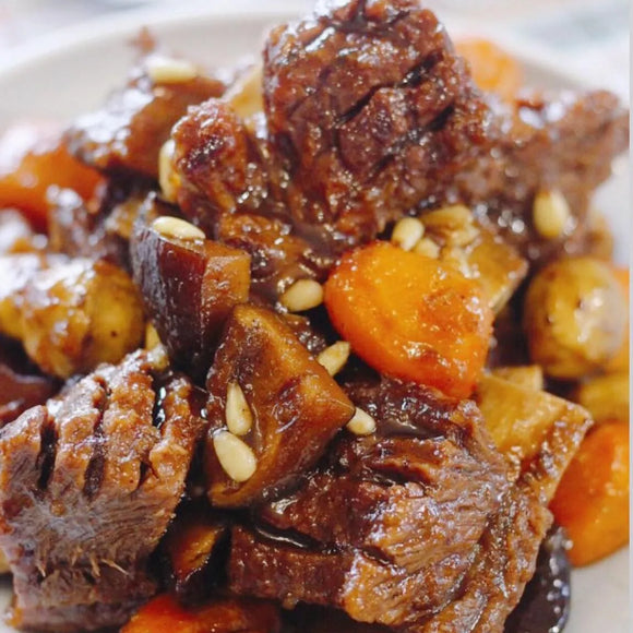 Stewed meat with carrots and pine nuts on a white plate
