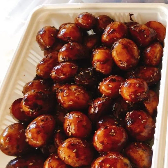 A platter of glazed baby potatoes with a savory sauce, likely to be a part of a Korean meal setup.