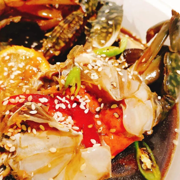 Korean soy-marinated raw crab dish garnished with sesame seeds and green onions.