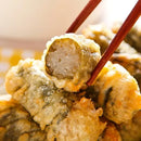 Fried food item with a bite taken out, held by chopsticks against a blurred background.