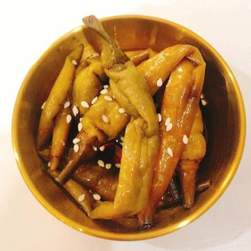 A gold bowl containing pickled Korean green chili peppers in a soy-based sauce, a traditional side dish known as Gochu Jangajji.