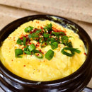 Korean steamed egg side dish in a black bowl on a wooden surface