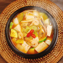 Korean Stew with various ingredients in a black bowl on a woven mat