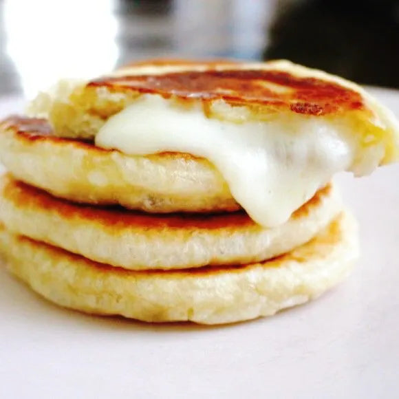 Stack of hotteok with a dollop of cheese on a white plate