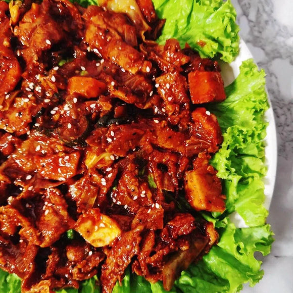 Korean spicy marinated stir-fry pork belly with vegetables served on a plate with lettuce.