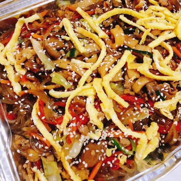A platter of Japchae, which is sweet potato noodles stir-fried with vegetables and ground pork, garnished with sesame seeds and crispy strips.