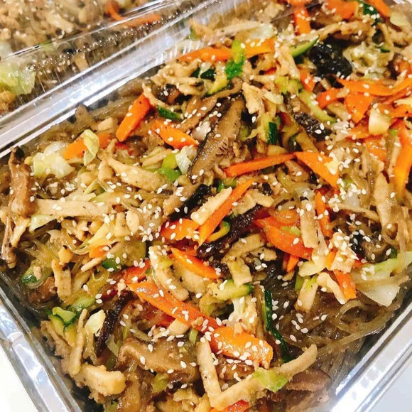 A platter of Japchae, which is sweet potato noodles stir-fried with vegetables and ground pork, garnished with sesame seeds and crispy strips.