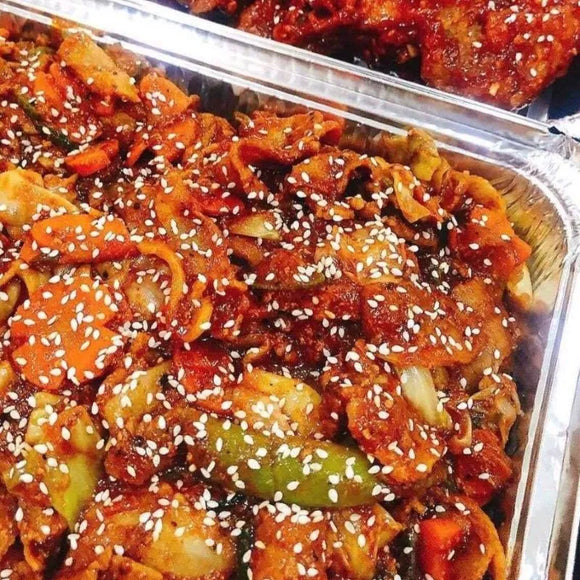 A platter of Korean spicy marinated stir-fry pork belly with vegetables, garnished with sesame seeds.