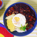 A bowl of unmixed Jjajangmyeon, which are noodles with a black bean sauce, garnished with a slice of lemon and a sprig of parsley.