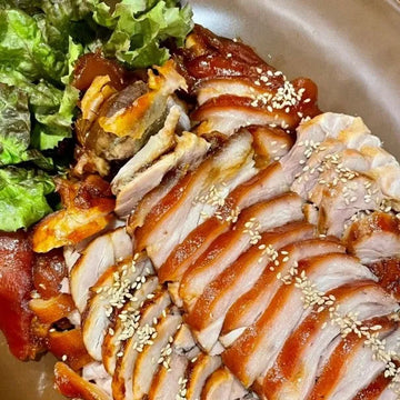 A dish of Jokbal, consisting of braised pig's trotters garnished with sesame seeds and served with a side of green salad.