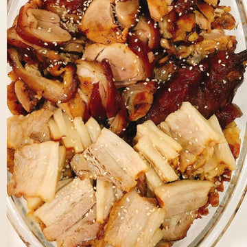 Plated dish of roasted meats with sesame seeds on a white background