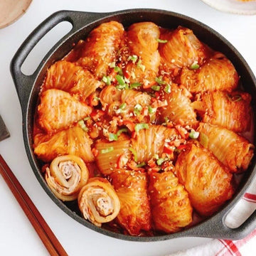 Baked stuffed rolls in a black skillet on a white surface