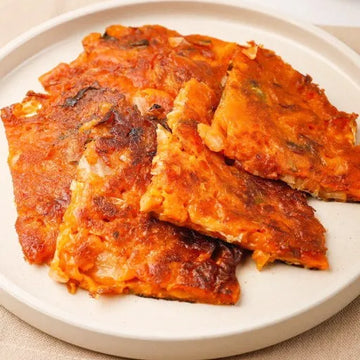 Stack of crispy Korean kimchi pancakes on a white plate
