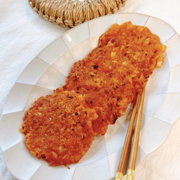 Three kimchi pancakes on a white plate with a gold fork.