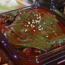 A plate of Korean perilla side dish (kkaenip-muchim) with visible chili flakes, seeds, and a mix of ingredients.