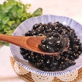 Dried black beans in a blue and white bowl with a wooden spoon