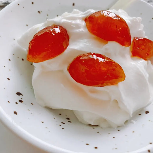 Whipped cream with Kumquat Jelly on a white plate with brown speckles