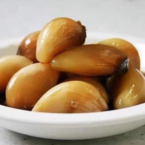 A bowl of cooked garlic cloves, likely to be used as a side dish or ingredient in Korean cuisine.