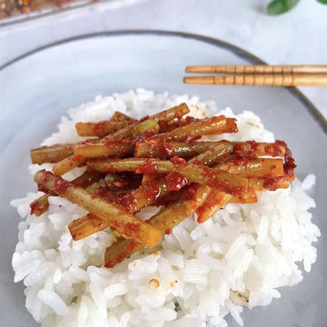 Spicy Seasoned Garlic Scrapes Banchan on a bed of white rice, served on a gray plate with chopsticks.