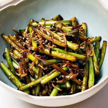 Bowl of stir-fried garlic scapes, accompanied by myeolchi (dried anchovies)