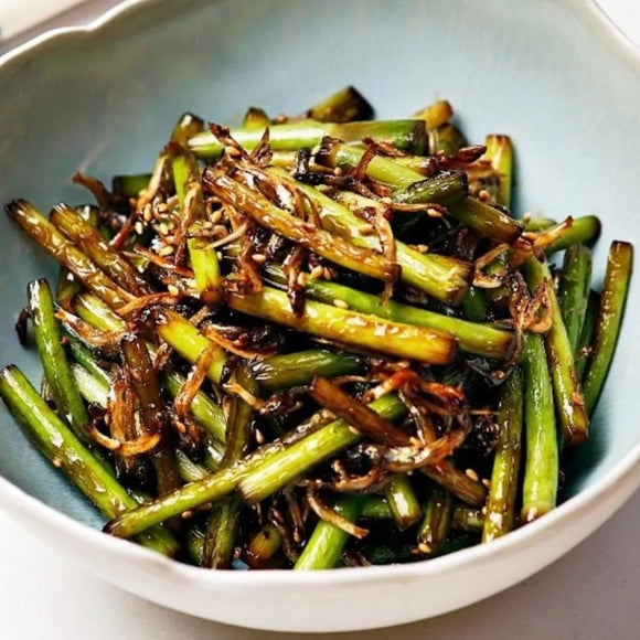 Bowl of stir-fried garlic scapes, accompanied by myeolchi (dried anchovies)