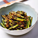 Bowl of stir-fried garlic scapes, accompanied by myeolchi (dried anchovies)