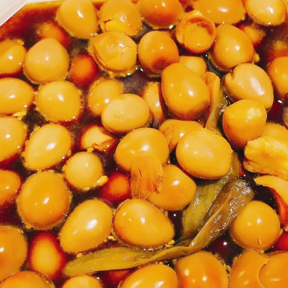 A platter of marinated quail eggs, with a glossy sauce and visible herbs and spices.