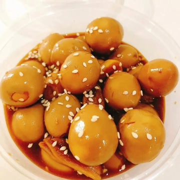 A bowl of quail eggs banchan with a sweet and savory marinade, garnished with sesame seeds.