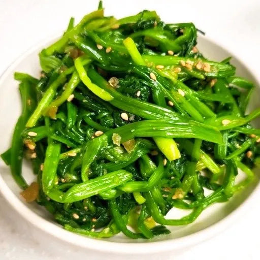 Korean seasoned banchan features fresh minari (Water Parsley) with sesame seeds on a white plate