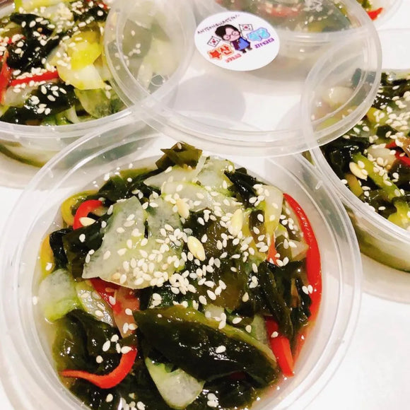 Container of seaweed salad with sesame seeds on a white surface