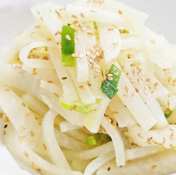 Korean Radish with green onions and sesame seeds on a white plate
