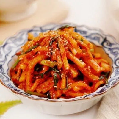 A bowl of julienne Korean radish salad with a spicy seasoning, commonly served as a side dish in Korean cuisine.