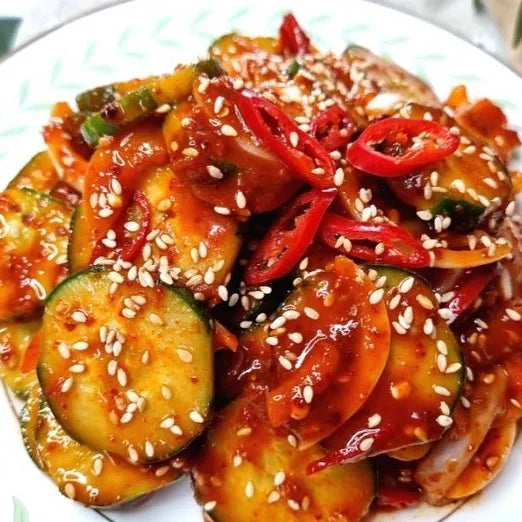 A plate of Korean cucumber mild spicy salad, garnished with sesame seeds and red chili slices.