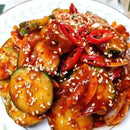 A plate of Korean cucumber mild spicy salad, garnished with sesame seeds and red chili slices.