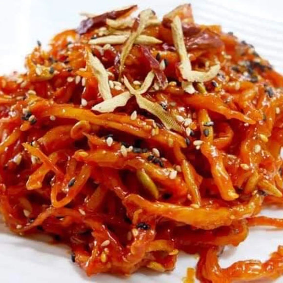 A plate of dried shredded squid seasoned with chili and other spices, garnished with sesame seeds and sliced scallions.