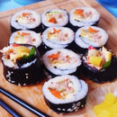 Pork Kimbap on a wooden cutting board with chopsticks.